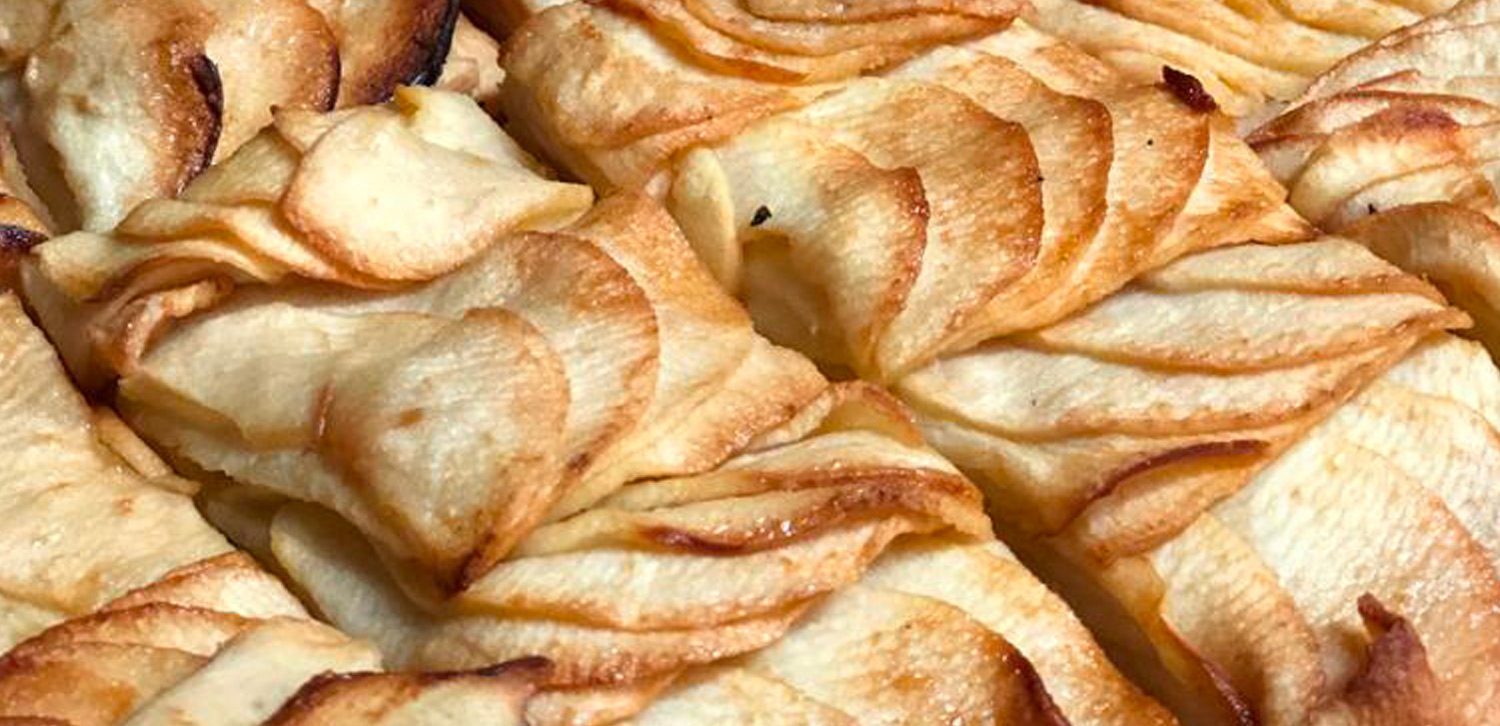 Golden-brown apple tarts with thinly sliced apple layers arranged in a decorative pattern on a buttery pastry base.